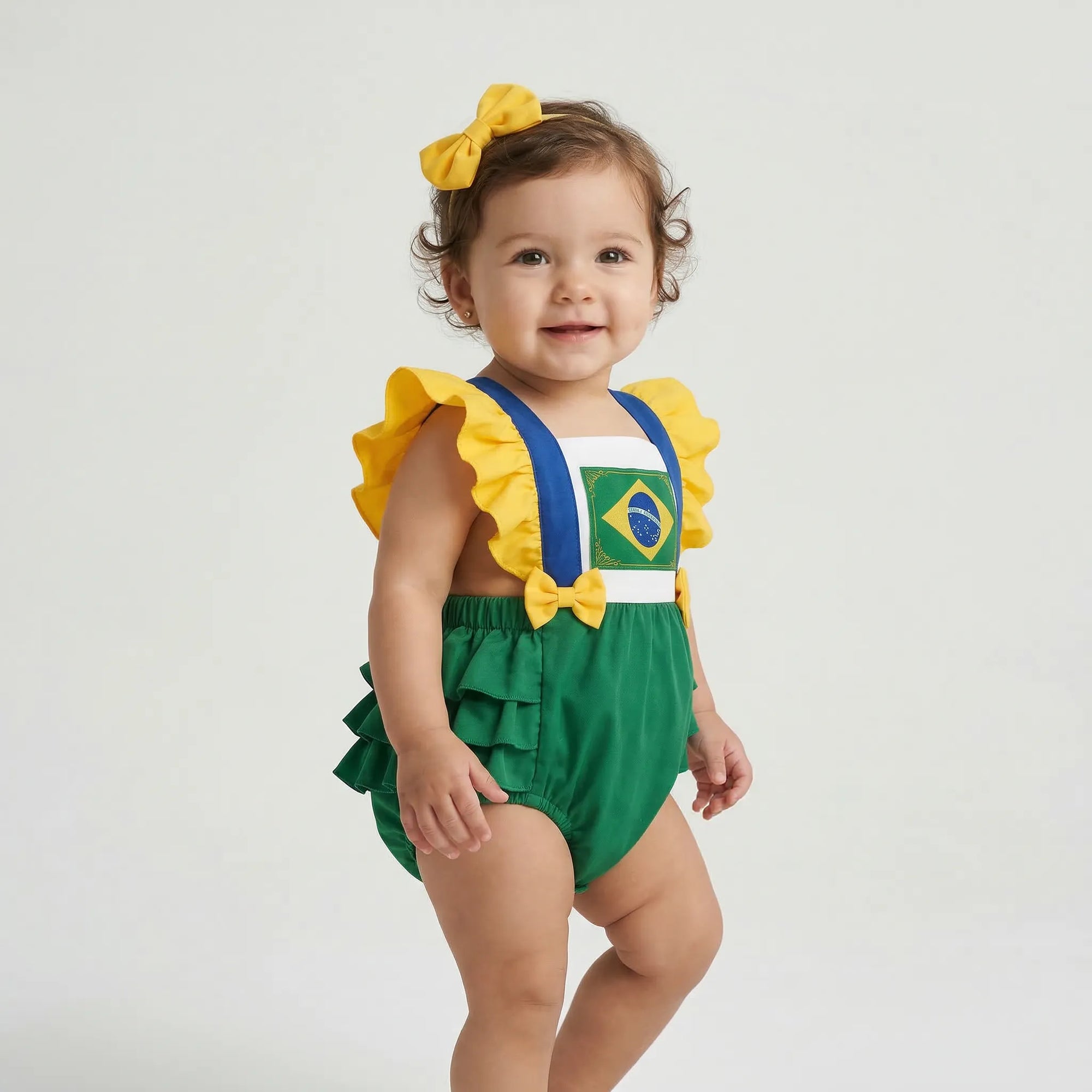 Bebê menina vestindo jardineira brasil tricoline verde amarelo bandeira VAI DAR BRASIL — torcedora Copa 2026