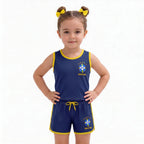 Menina vestindo conjunto infantil feminino brasil brasão seleção blusa short azul marinho — look torcida Copa 2026 VAI DAR BRASIL