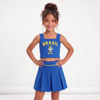 Menina vestindo conjunto infantil saia plissada cropped brasil brasão azul — look Copa 2026 VAI DAR BRASIL charme elegante
