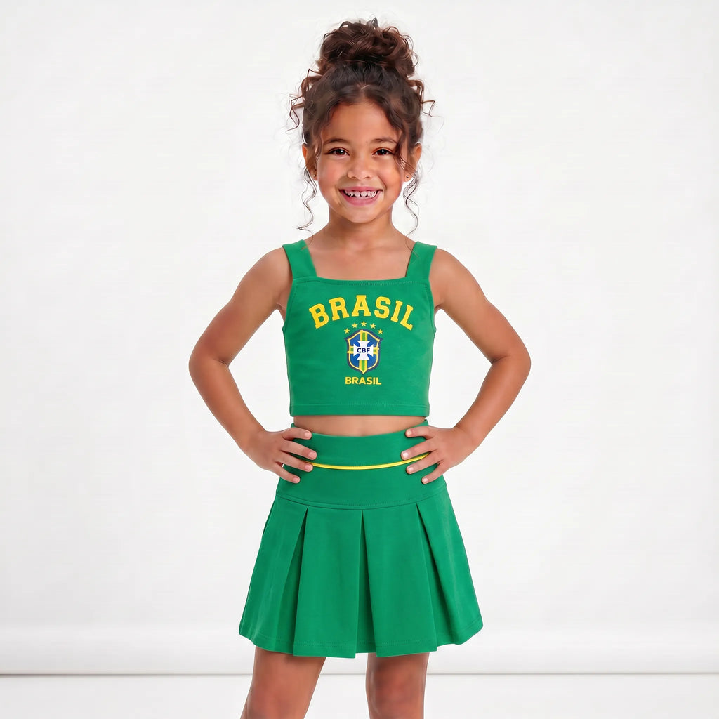 Menina vestindo conjunto infantil saia plissada cropped brasil brasão verde — look Copa 2026 VAI DAR BRASIL charme elegante