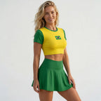 Mulher vestindo conjunto brasil cropped manga short saia suplex slim bandeira amarela VAI DAR BRASIL — torcedora Copa 2026